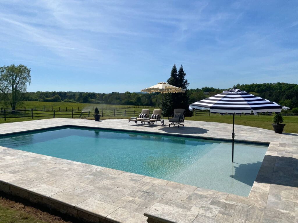 pool with lounge chairs and umbrellas and countryside in the background