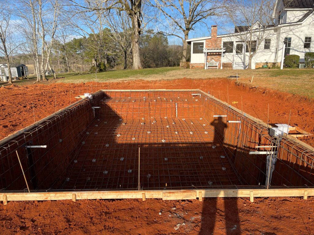 a pool that is under construction in a yard with a house in the back ground